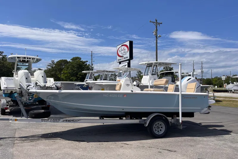 The Image of 2016 Tidewater 1910 Bay Max boat on trailer at dealership under clear blue sky. - 1