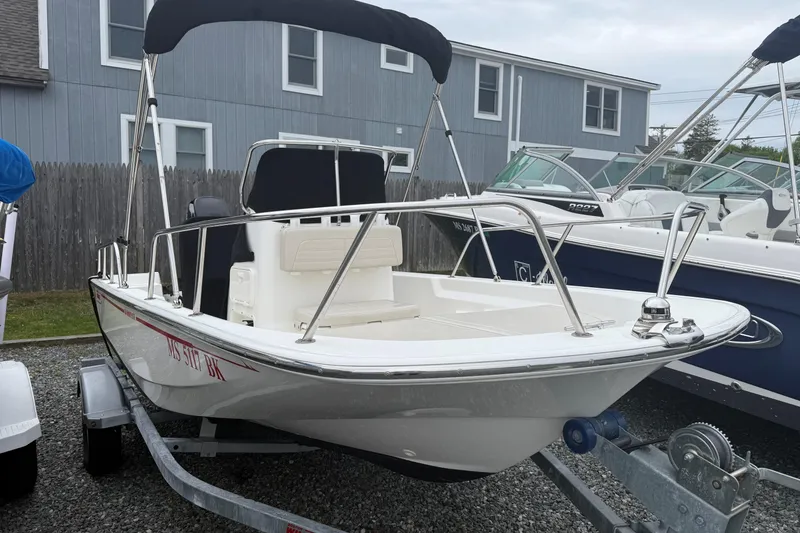 Slide: The Image of 2019 Boston Whaler 150 Montauk boat on trailer, parked outdoors with canopy. - 2
