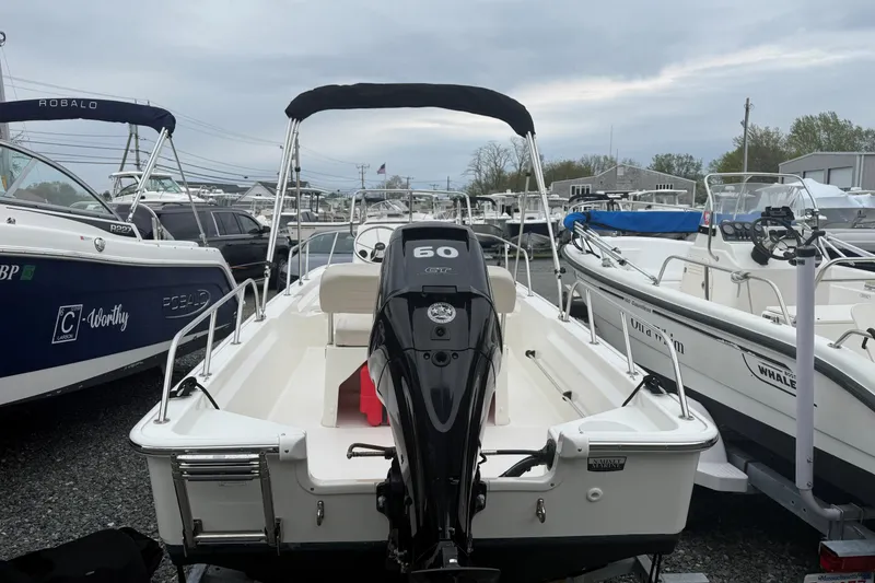Slide: The Image of 2019 Boston Whaler 150 Montauk boat with 60 HP engine, docked among other boats. - 3