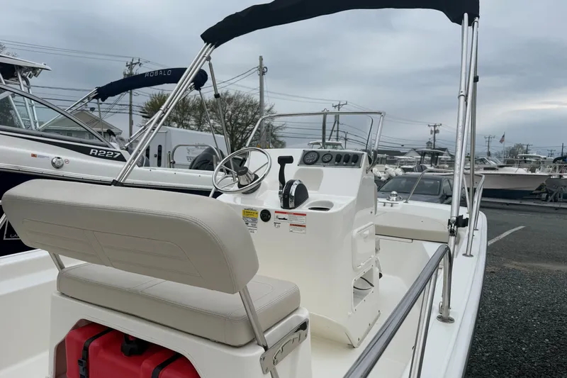 Slide: The Image of 2019 Boston Whaler 150 Montauk boat with steering console and seating, docked outdoors. - 9