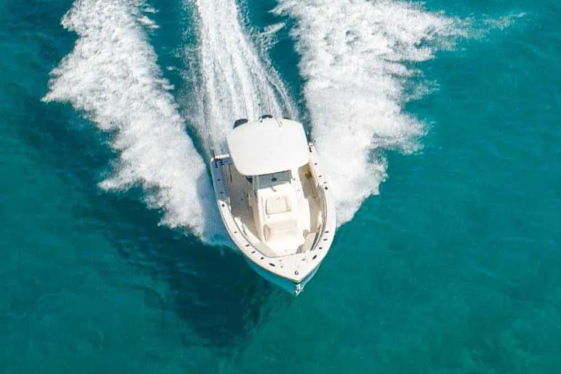 Slide: The Image of Manufacturer Provided Image: 2022 Cobia 262 Center Console boat cruising on clear blue water. - 2