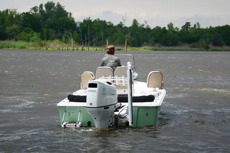 Slide: The Image of 2023 Sea Pro 228 Bay boat navigating a river with lush green shoreline. - 4