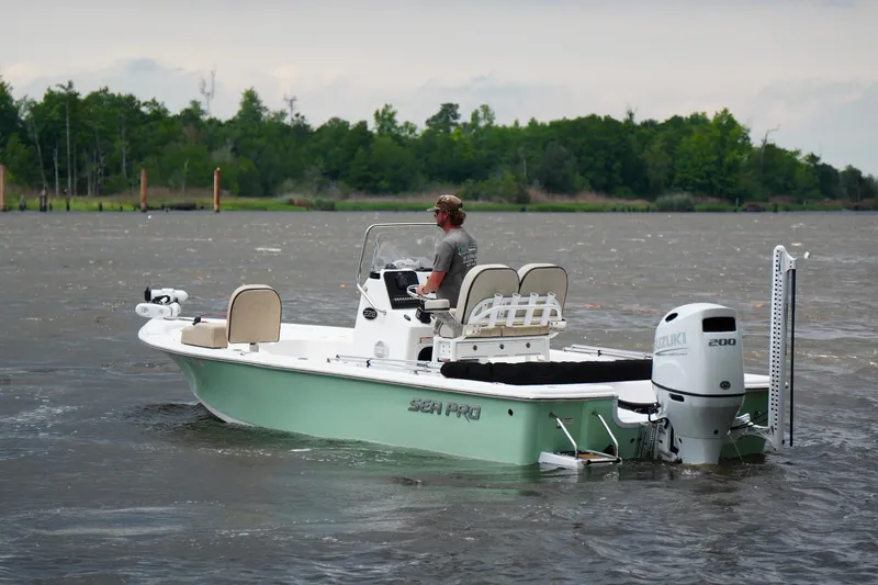 Slide: The Image of 2023 Sea Pro 228 Bay boat cruising on a lake with lush green shoreline. - 5
