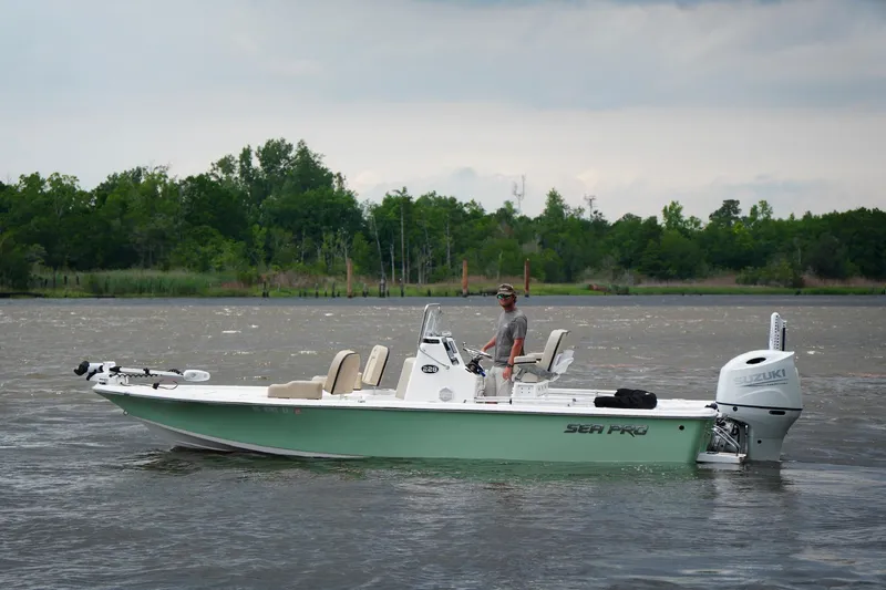 Slide: The Image of 2023 Sea Pro 228 Bay boat on a calm river with lush green trees in the background. - 6