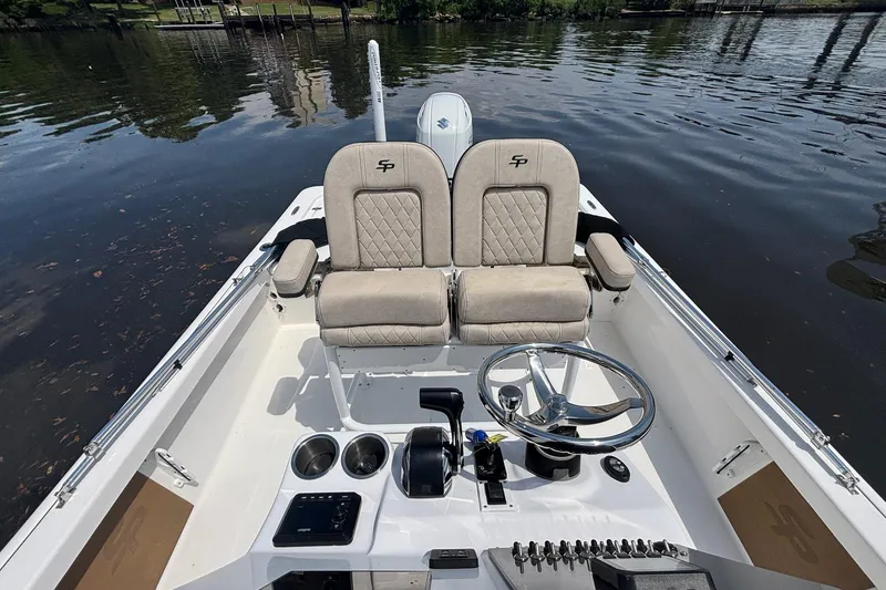Slide: The Image of 2023 Sea Pro 228 Bay boat interior with dual seats and steering wheel on calm water. - 9