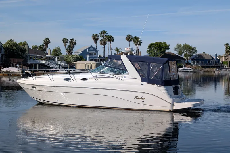 The Image of 2003 Rinker Fiesta Vee 342 boat on calm water, with houses and palm trees in the background. - 0