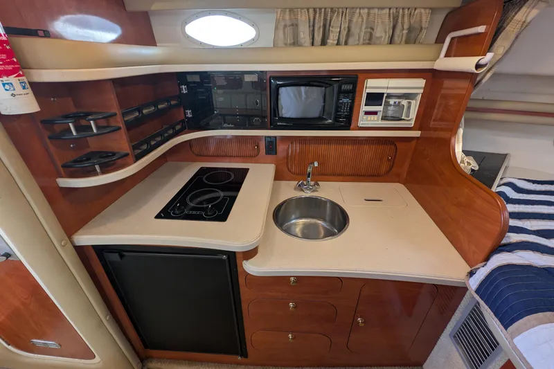 Slide: The Image of 2003 Rinker Fiesta Vee 342 boat kitchen with stove, sink, microwave, and storage. - 33