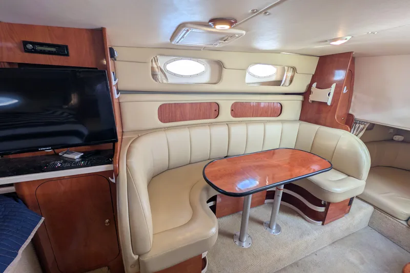 Slide: The Image of 2003 Rinker Fiesta Vee 342 cabin interior with leather seating, wooden table, and mounted TV. - 37