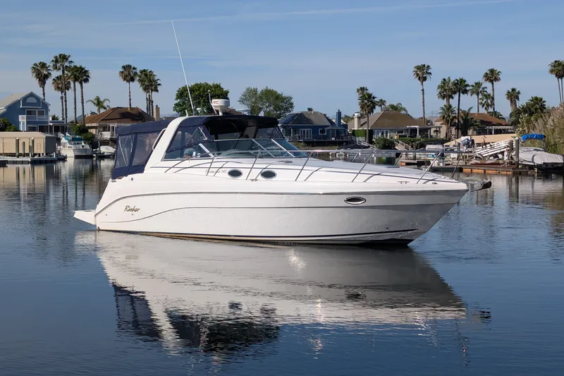 Slide: The Image of 2003 Rinker Fiesta Vee 342 yacht on calm water, surrounded by palm trees and waterfront homes. - 6