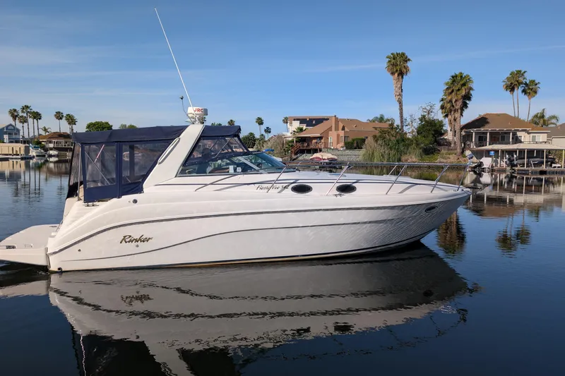 Slide: The Image of 2003 Rinker Fiesta Vee 342 boat docked on calm water with palm trees in the background. - 8