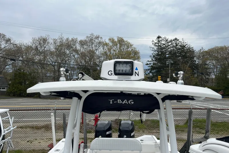 Slide: The Image of 2005 Angler 2700CC boat with T-top and navigation equipment, parked outdoors. - 13