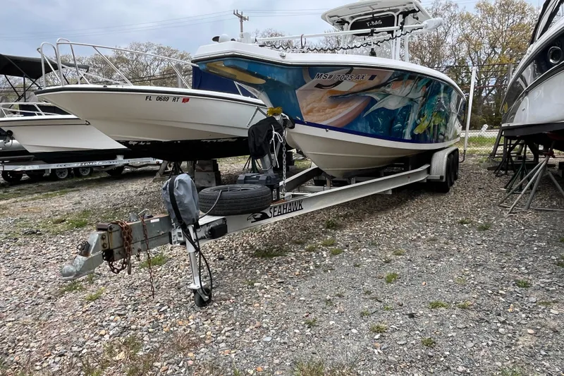 Slide: The Image of 2005 Angler 2700CC boat on trailer with vibrant marine artwork, parked outdoors. - 31