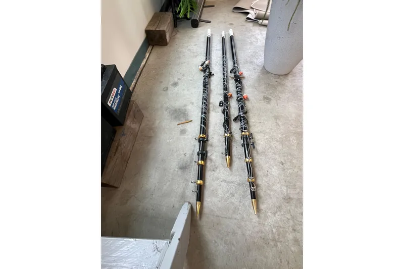 Slide: The Image of Three fishing rods with gold tips on a concrete floor, near a marine battery. - 37
