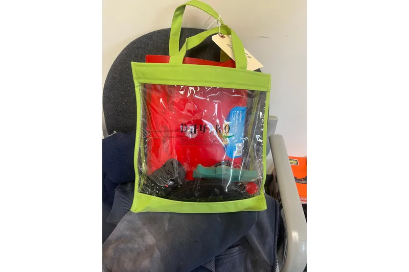 Slide: The Image of Clear tote bag with green trim containing various items, placed on a chair. - 38