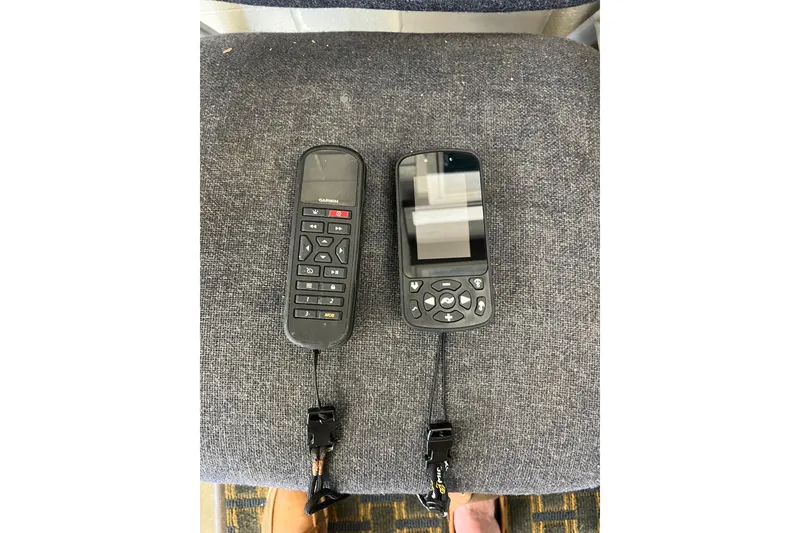 Slide: The Image of Two Garmin marine remote controls on a gray fabric surface, related to a 2005 Angler 2700CC boat. - 40