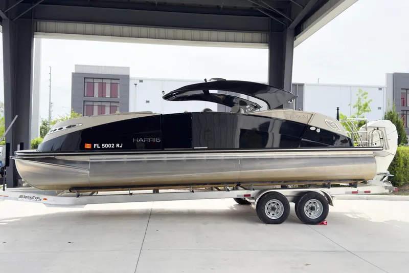 Slide: The Image of 2017 Harris Crowne 250 pontoon boat on trailer, parked under a shelter. - 4