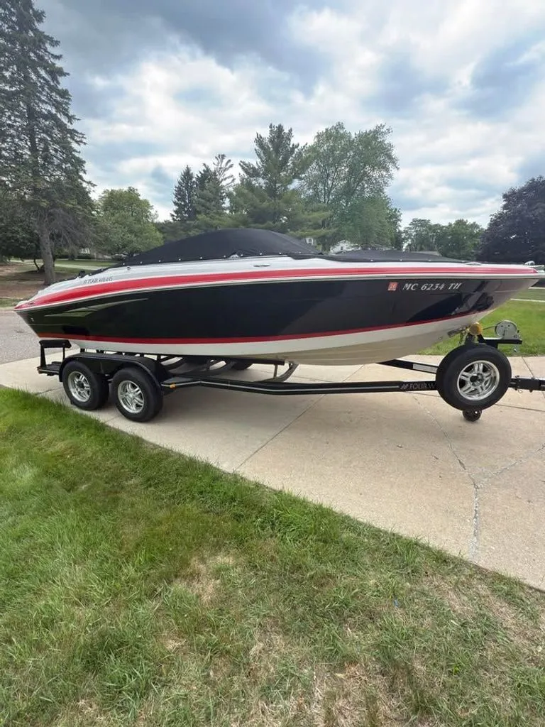The Image of 2010 Four Winns H210 boat parked on trailer outdoors. - 0