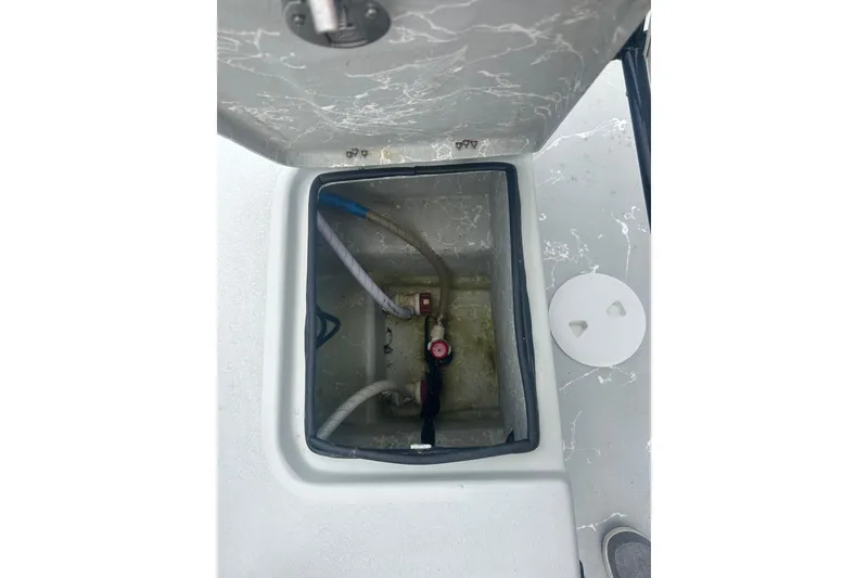 Slide: The Image of Open compartment of a 2025 Skuta 24 boat showing internal plumbing and hoses. - 18