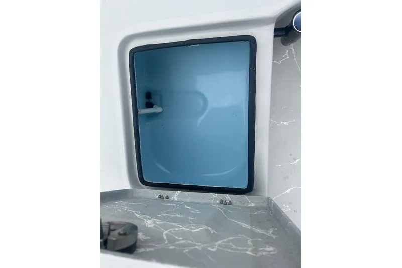 Slide: The Image of Open storage compartment in Skuta 24 boat, 2025 model, with blue interior and gray exterior. - 20