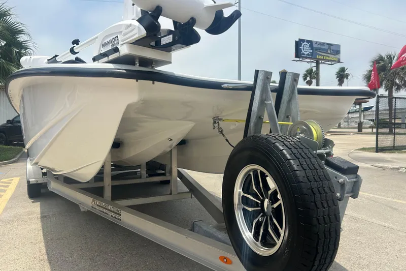 Slide: The Image of 2025 Skuta 24 boat on trailer with Minn Kota motor, parked outdoors. - 3