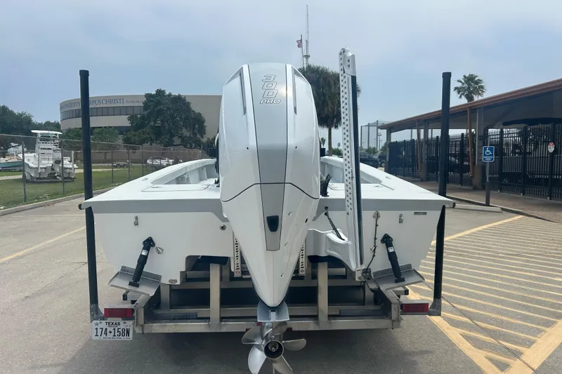 Slide: The Image of 2025 Skuta 24 boat on trailer with powerful outboard motor, parked near university campus. - 5