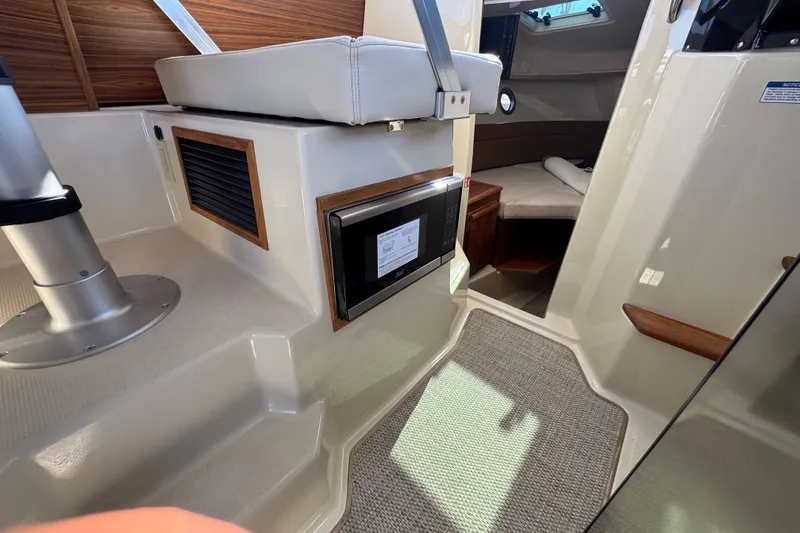 Slide: The Image of Interior of 2026 Ranger Tugs R-25 boat, featuring seating and compact cabin space. - 19