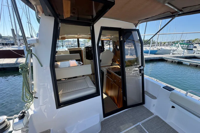 Slide: The Image of 2026 Ranger Tugs R-25 boat interior view at marina, showcasing seating and helm area. - 10