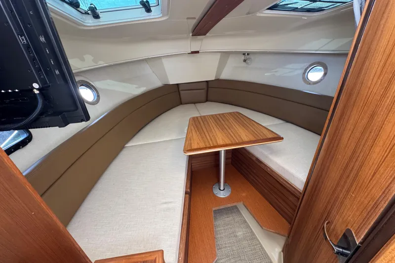 Slide: The Image of 2026 Ranger Tugs R-25 cabin interior with cozy seating and wooden table. - 22
