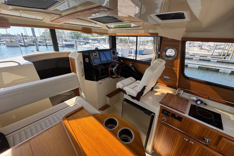 Slide: The Image of Interior of 2026 Ranger Tugs R-25 boat, featuring helm, seating, and kitchenette. - 16