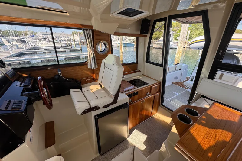 Slide: The Image of Interior of 2026 Ranger Tugs R-25 boat, featuring helm, seating, and kitchenette. - 17