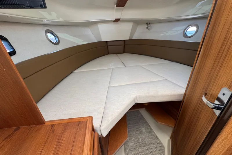Slide: The Image of 2026 Ranger Tugs R-25 cabin interior with cozy bed and wooden accents. - 23