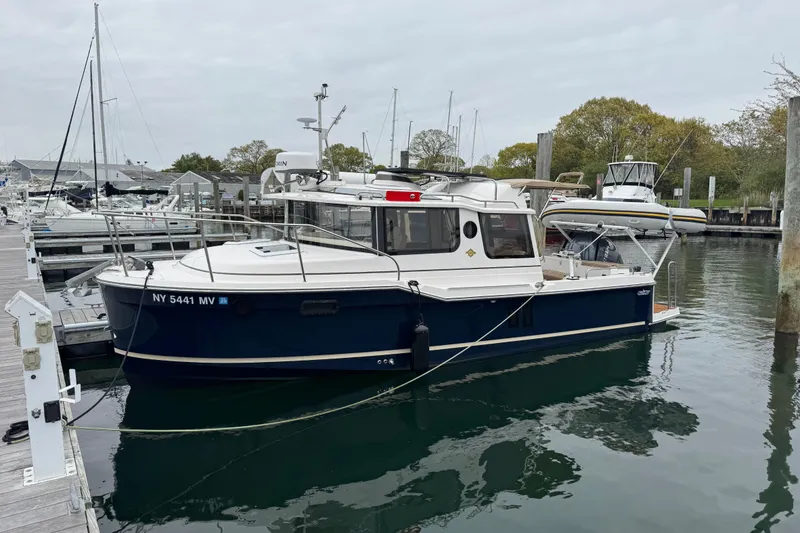 Slide: The Image of 2026 Ranger Tugs R-25 boat docked in a marina, featuring a sleek design and modern amenities. - 3