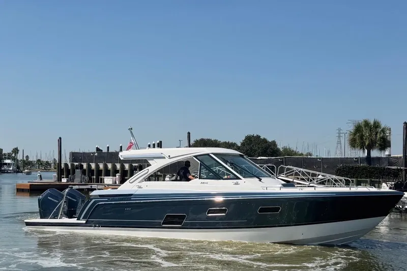 Slide: The Image of 2026 Formula 380 Super Sport Crossover OB boat docked in a marina under clear blue skies. - 3