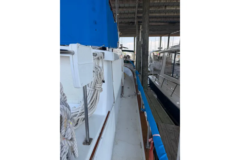 Slide: The Image of 1978 Albin 36 Trawler docked, featuring deck ropes and blue canopy. - 10