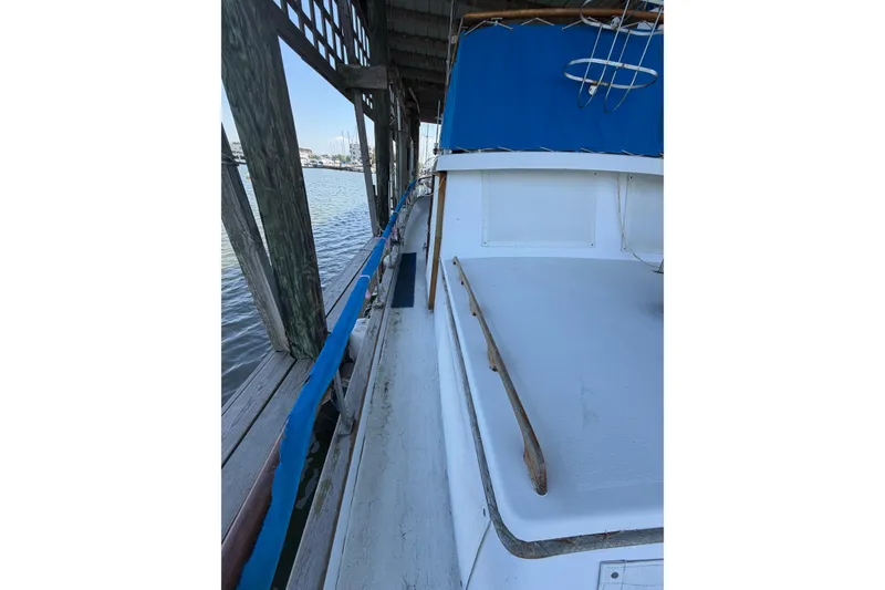 Slide: The Image of 1978 Albin 36 Trawler docked, showcasing side deck and blue canopy. - 12