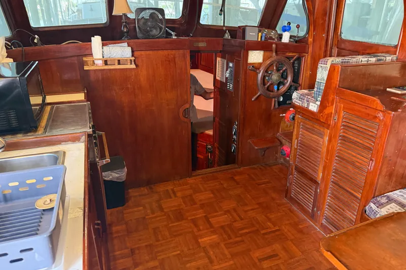 Slide: The Image of 1978 Albin 36 Trawler interior with wooden finish, steering wheel, and kitchenette area. - 13