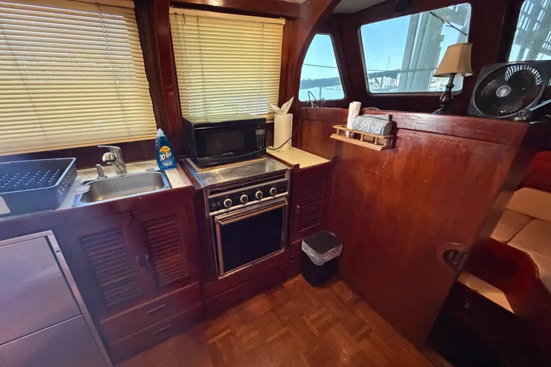 Slide: The Image of 1978 Albin 36 Trawler kitchen with wooden cabinetry, stove, and microwave. - 16