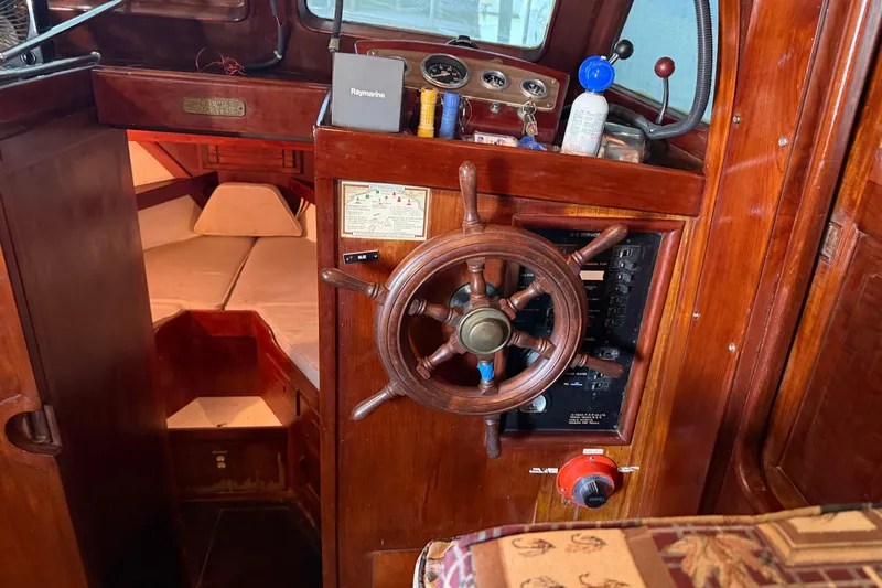 Slide: The Image of 1978 Albin 36 Trawler interior with wooden helm, gauges, and cozy cabin space. - 17