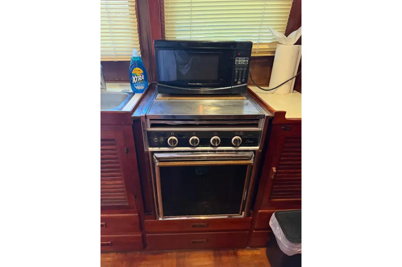Slide: The Image of 1978 Albin 36 Trawler kitchen with microwave, oven, and cleaning supplies. - 28