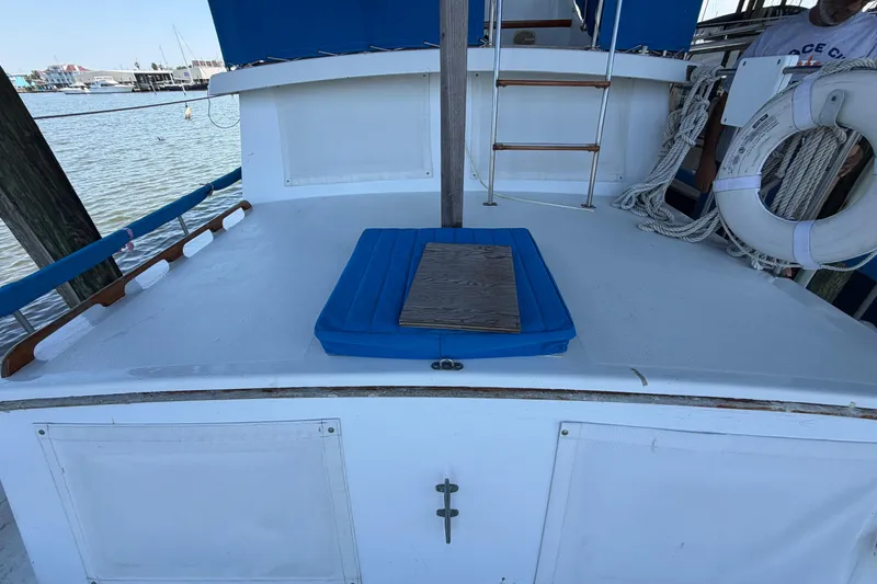 Slide: The Image of 1978 Albin 36 Trawler deck with blue cushion, ladder, and life preserver by the dock. - 5