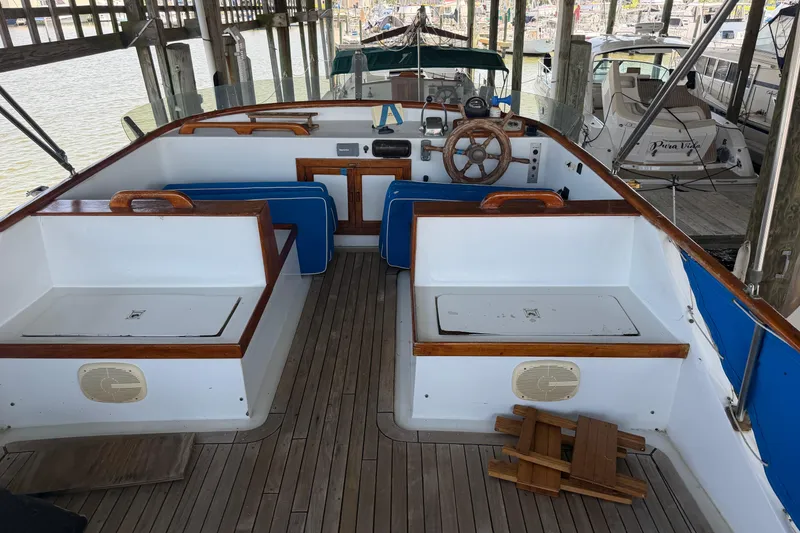 Slide: The Image of 1978 Albin 36 Trawler interior with wooden accents and blue cushions, docked in a marina. - 6