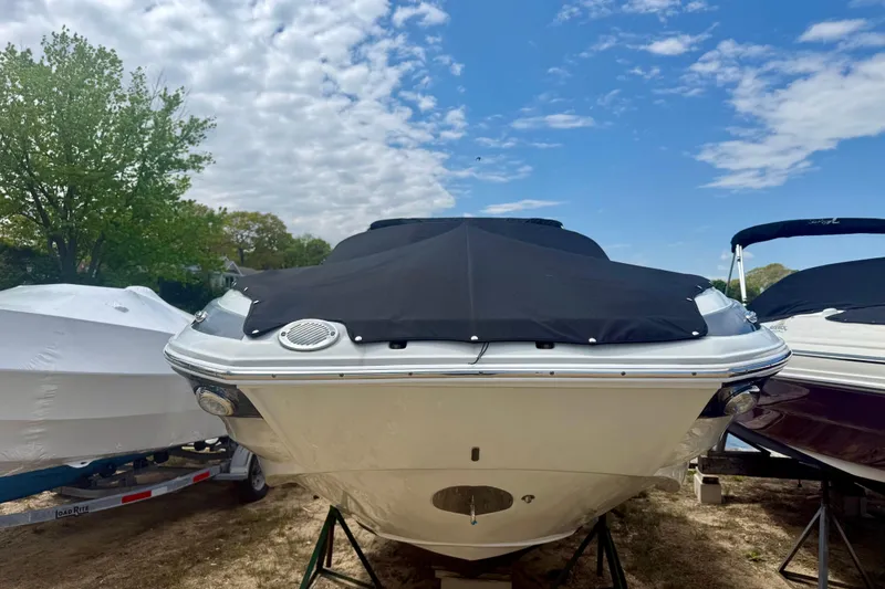 Slide: The Image of 2020 Crownline Eclipse E235 boat with black cover, parked outdoors under a blue sky. - 19