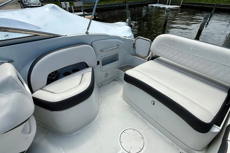 Slide: The Image of 2020 Crownline Eclipse E235 boat interior with white seating and black accents, docked by the water. - 29