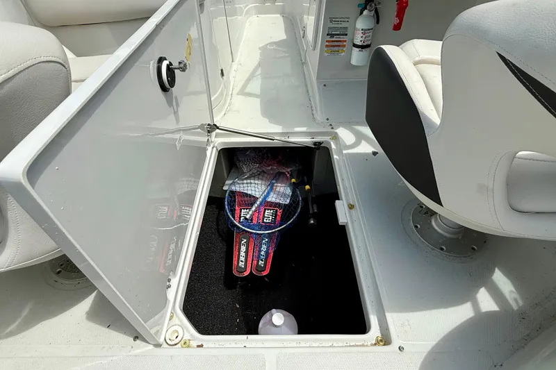 Slide: The Image of Open storage compartment in 2020 Crownline Eclipse E235 boat, containing sports equipment. - 30
