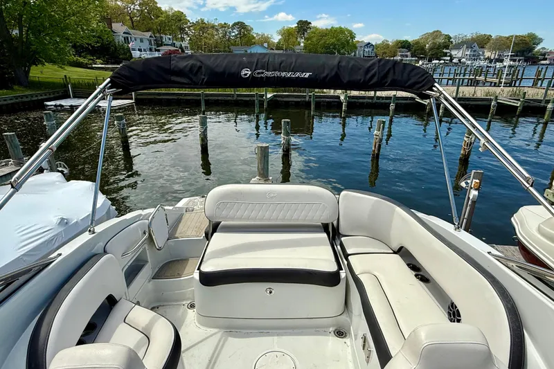 Slide: The Image of 2020 Crownline Eclipse E235 boat interior with seating, docked by a scenic waterfront. - 38