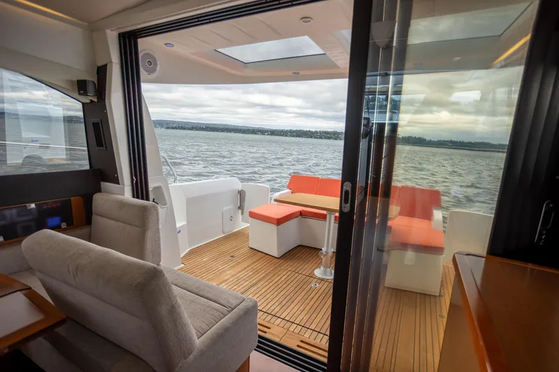 Slide: The Image of 2017 Jeanneau NC 14 yacht interior with cozy seating and scenic water view. - 7
