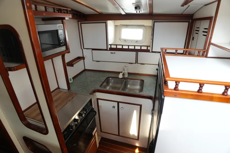 Slide: The Image of 1960 Matthews 42 Stock Cruiser kitchen with wood accents, stove, microwave, and sink. - 22