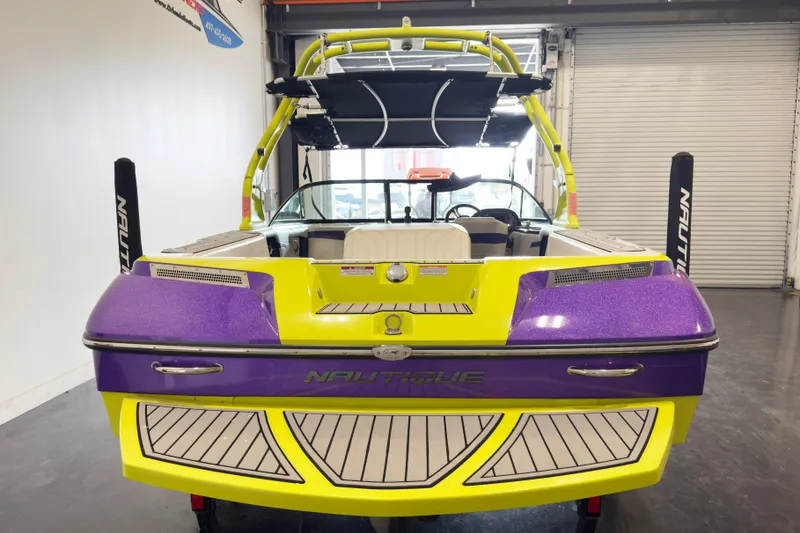 Slide: The Image of 2014 Nautique Ski Nautique 200 Closed Bow in vibrant yellow and purple, rear view in garage. - 5