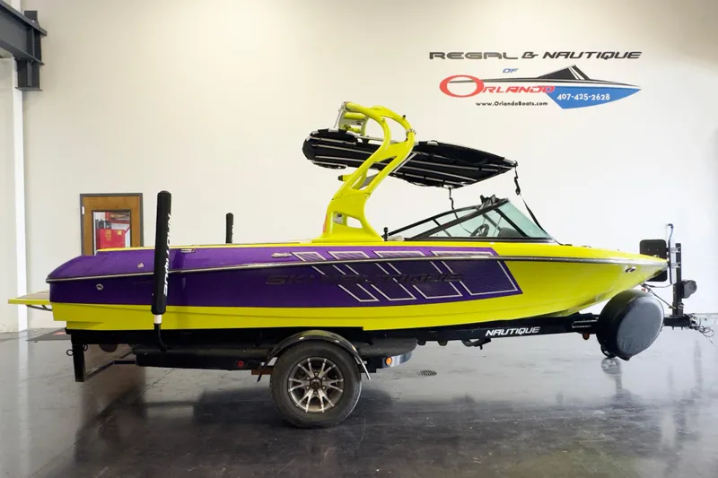 The Image of 2014 Nautique Ski Nautique 200 Closed Bow in vibrant yellow and purple on trailer. - 1