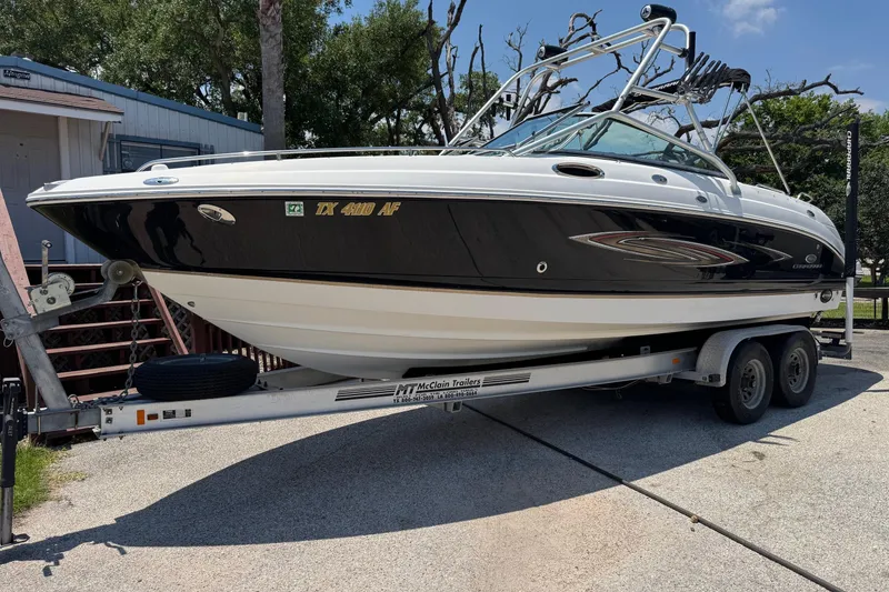 The Image of 2006 Chaparral 256 SSi boat on trailer, black and white design, parked outdoors. - 0